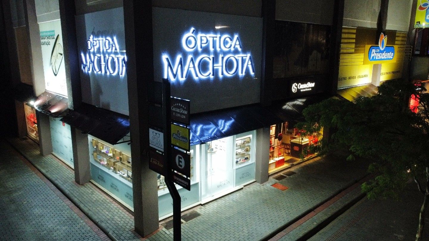 Fachada da Óptica Machota iluminada à noite